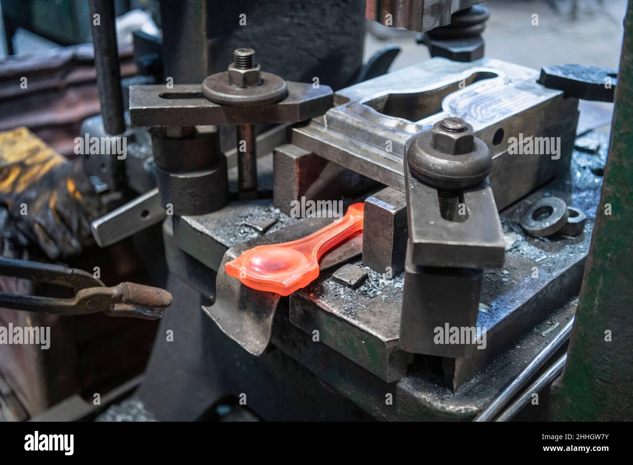 Cutting waste off titanium forged part in industrial forge Stock Photo
