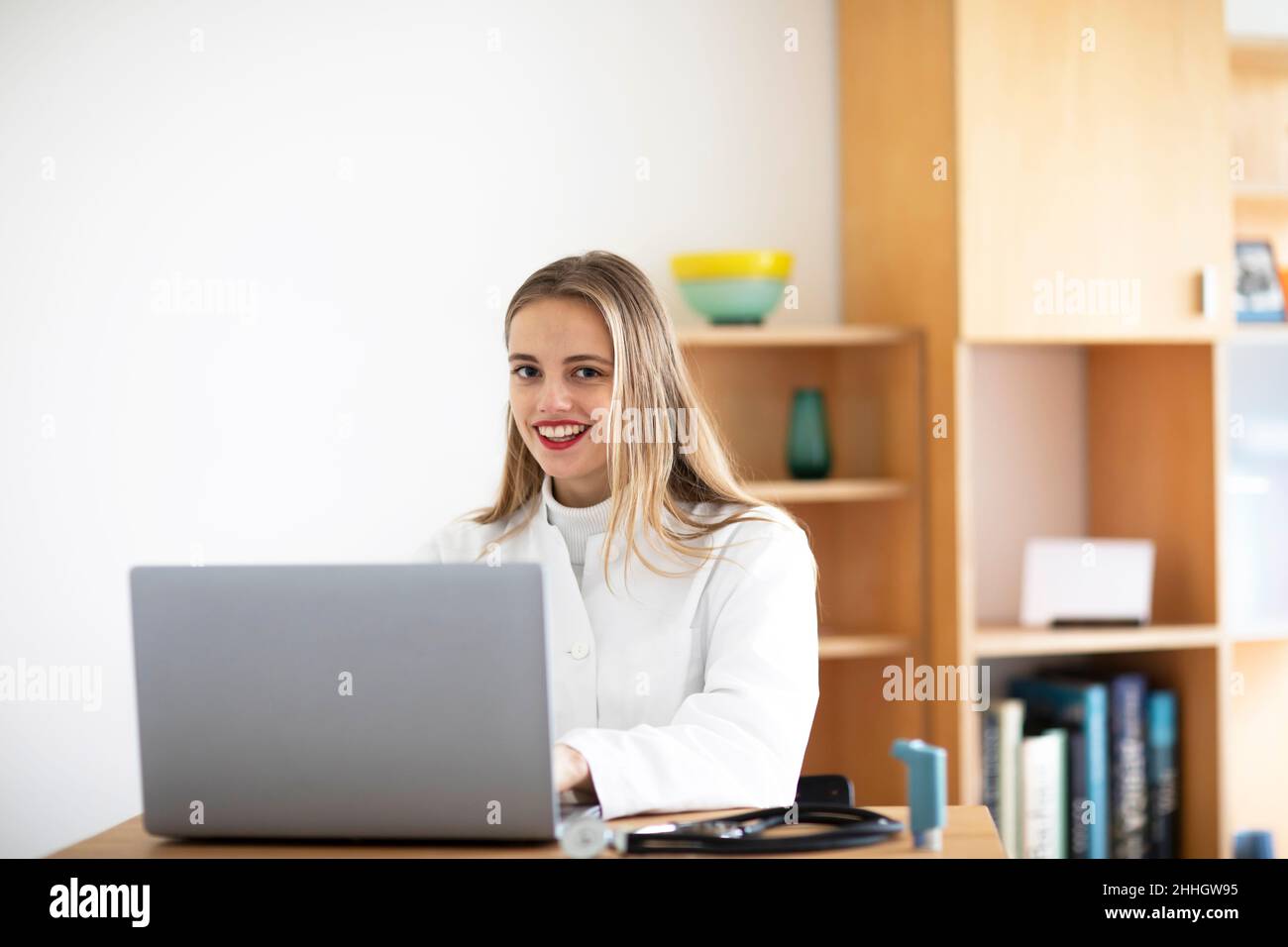 Smiling young female doctor using laptop Stock Photo