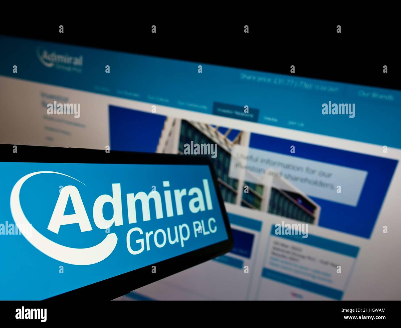 Cellphone with logo of British insurance company Admiral Group plc on screen in front of business website. Focus on left of phone display. Stock Photo
