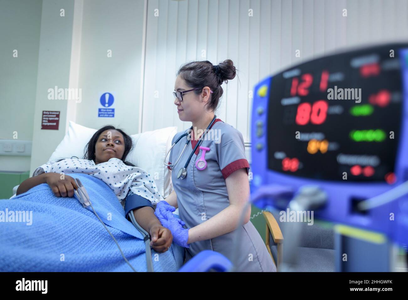 Nurse checking patients blood pressure on hospital ward Stock Photo