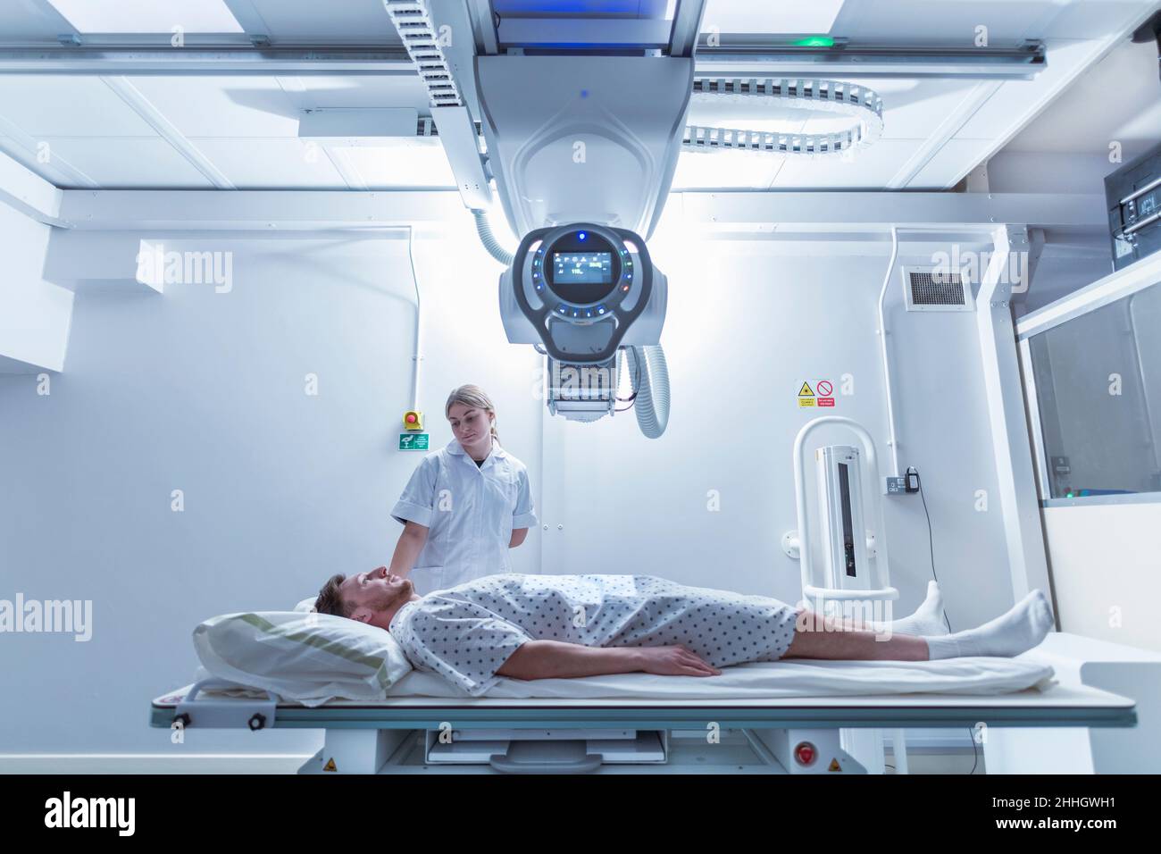Radiologist assisting patient atÊx-ray machine in hospital Stock Photo