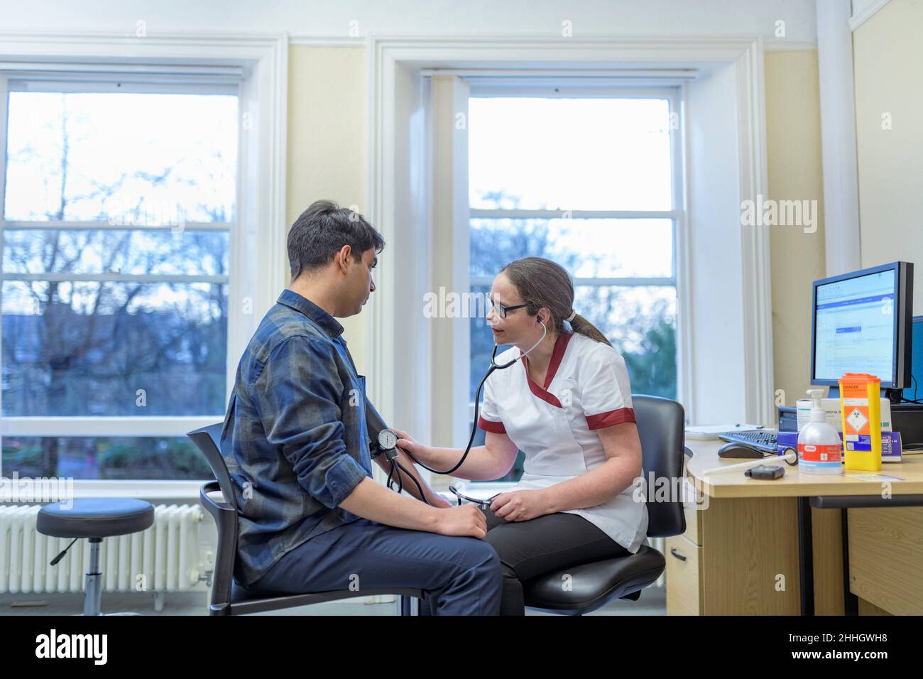 Nurse checking patients blood pressure in doctors office Stock Photo