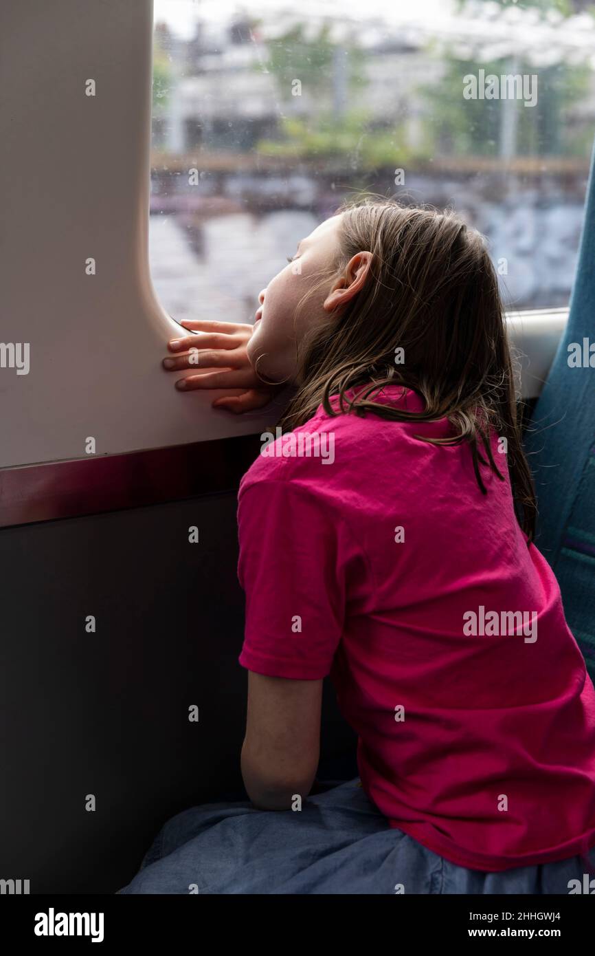 Girl Êlooking through window in train Stock Photo