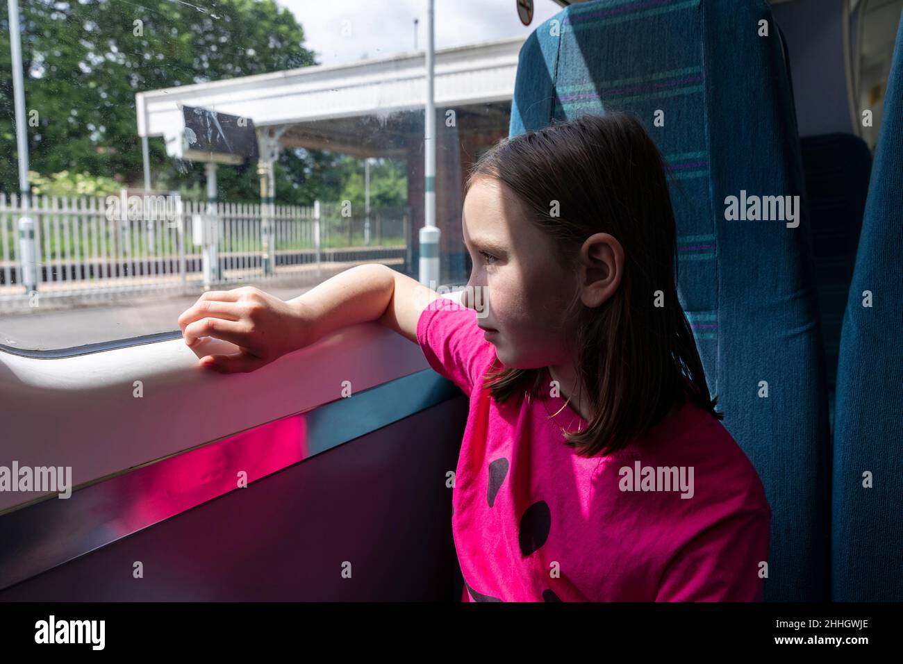 Girl Êlooking through window in train Stock Photo