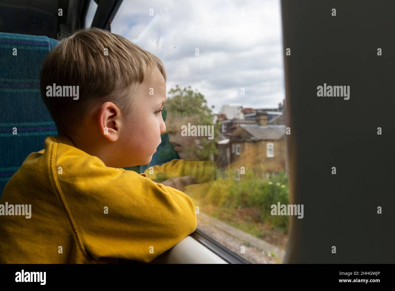 Boy Êlooking through window in train Stock Photo