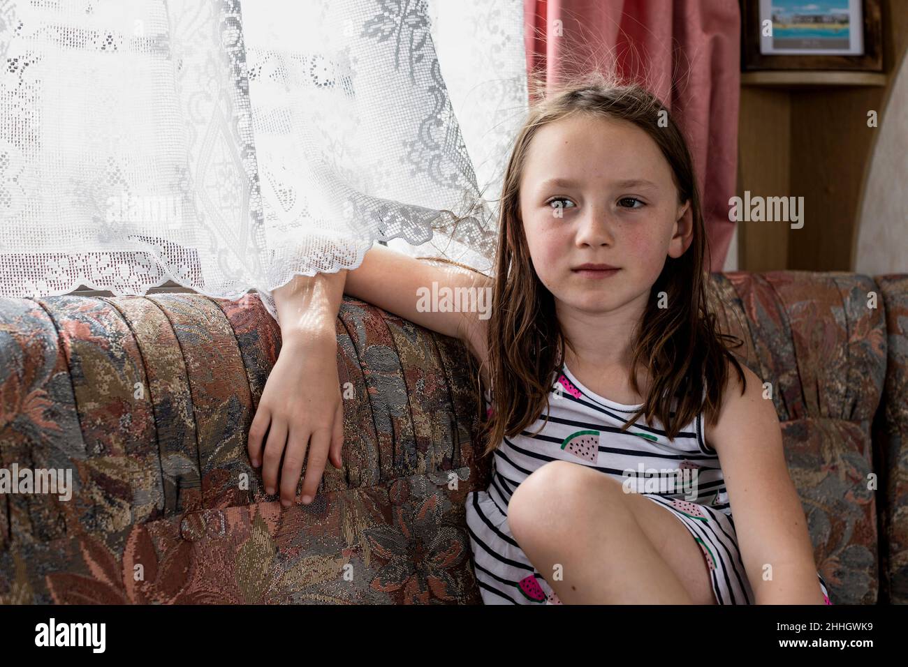 Portrait of girl sitting on sofa in caravan Stock Photo