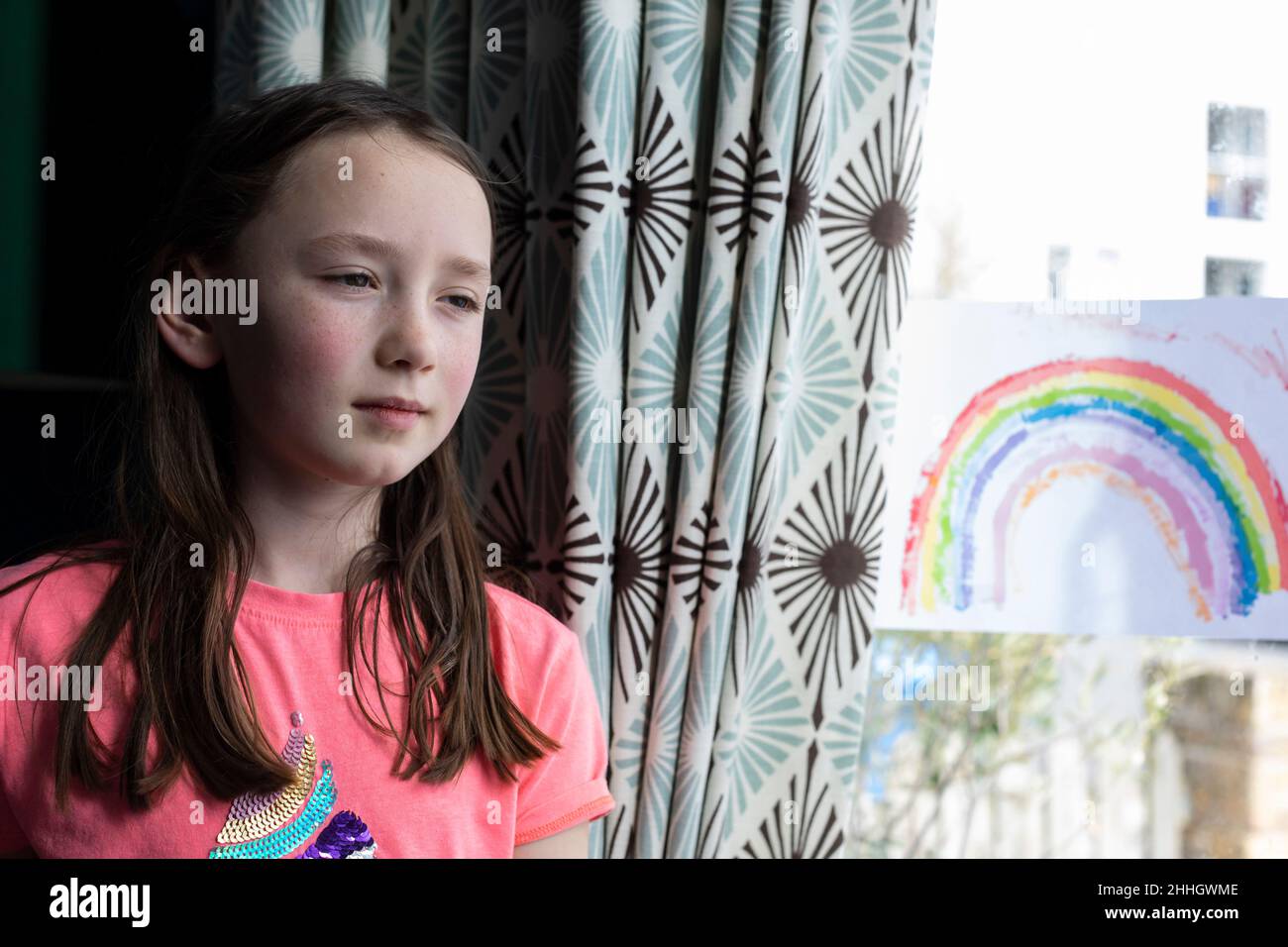 Girl by window with drawing of rainbow Stock Photo