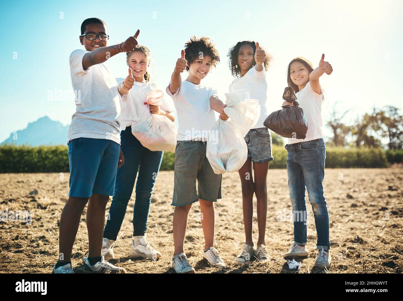 All green, all green, all good. Shot of a group of teenagers picking up litter off a field and showing thumbs up at summer camp. Stock Photo