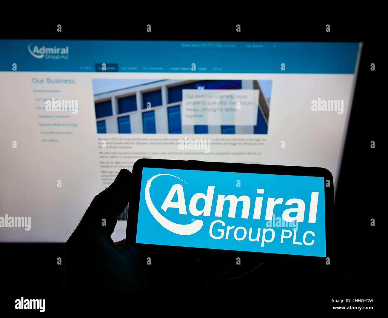 Person holding smartphone with logo of British insurance company Admiral Group plc on screen in front of website. Focus on phone display. Stock Photo