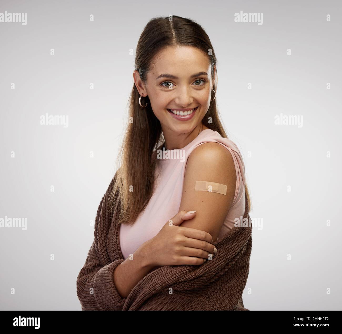 Vaccine shots tequila shots. Shot of a young woman standing alone in the studio after getting vaccinated. Stock Photo