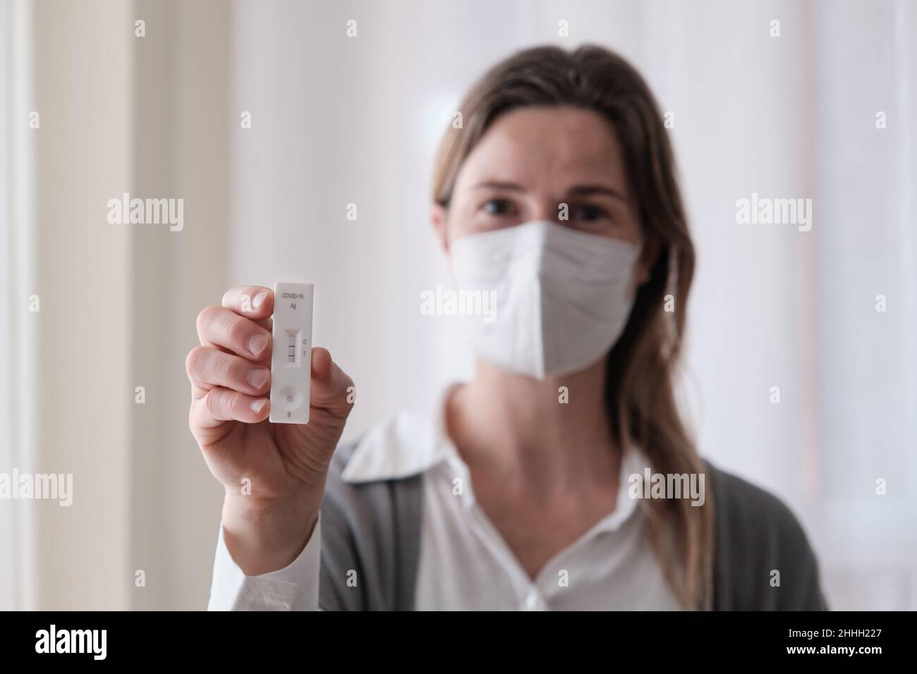Woman holding an antigen test with positive result. Stock Photo