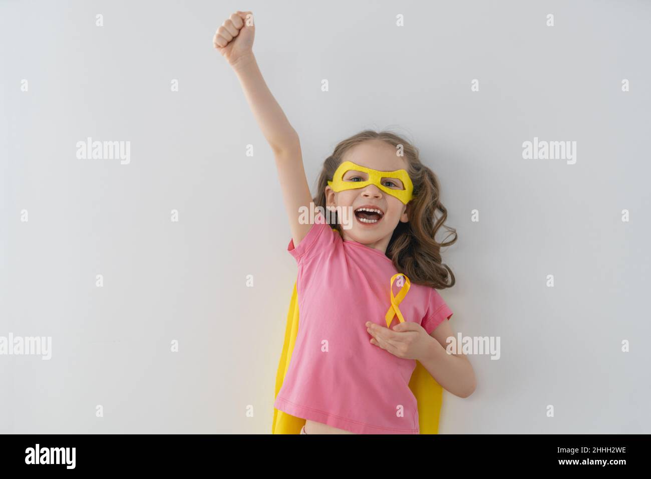 World Childhood cancer Day. Girl in superhero costume with golden ...