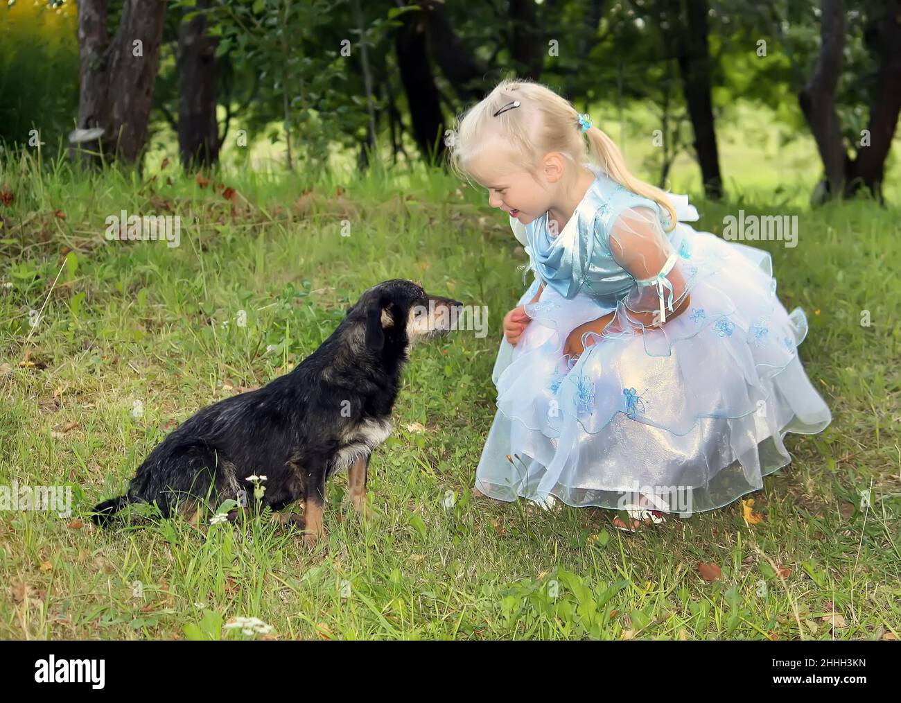 A little blonde girl with a dog in the summer garden Stock Photo - Alamy