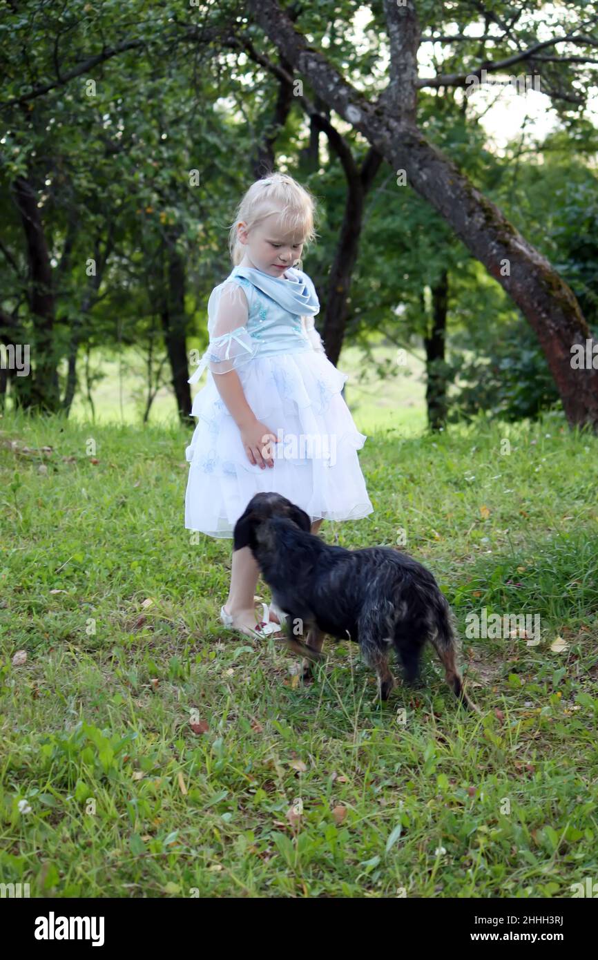 A little blonde girl with a dog in the summer garden Stock Photo - Alamy