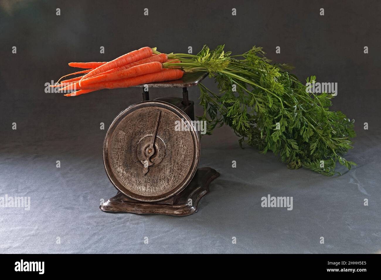 Portrait of a vintage kitchen scale weighinga bunch of brightly colored organic carrots. Stock Photo