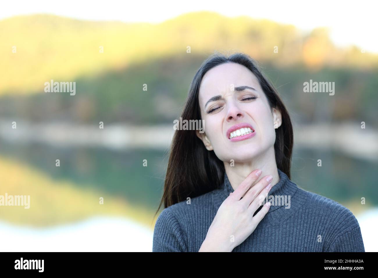 Front view portrait of a woman suffering sore throat complaining in nature Stock Photo