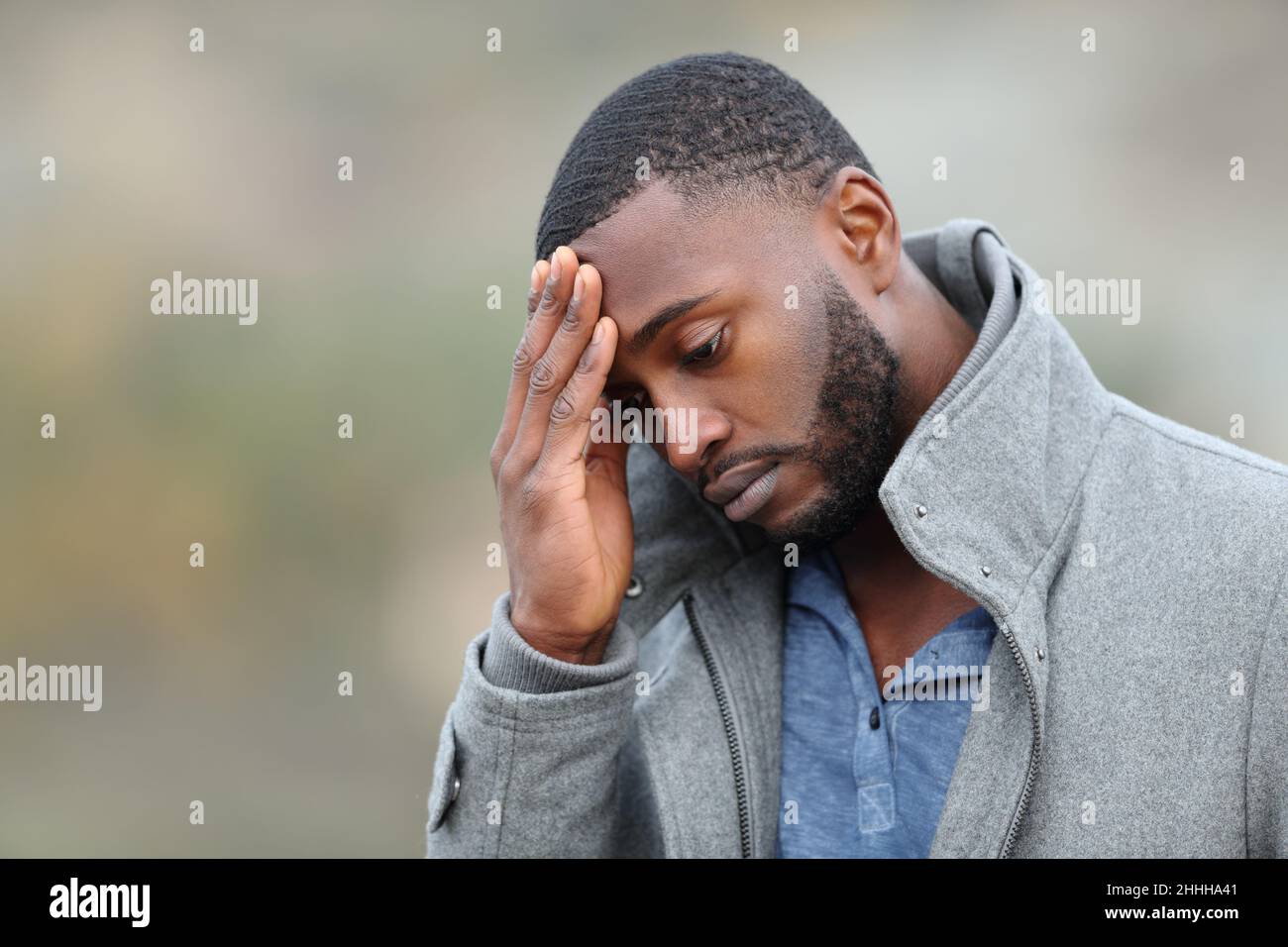 Worried man with black skin complaining in winter walking in a park Stock Photo