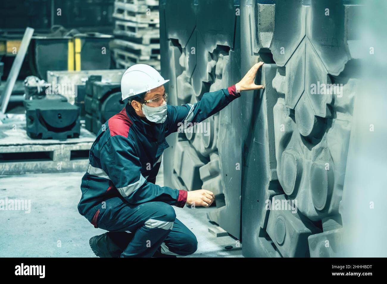 Quality control inspector in factory. Unrecognizable engineer in hard hat, workwear and face mask in workplace in metallurgy plant. Stock Photo