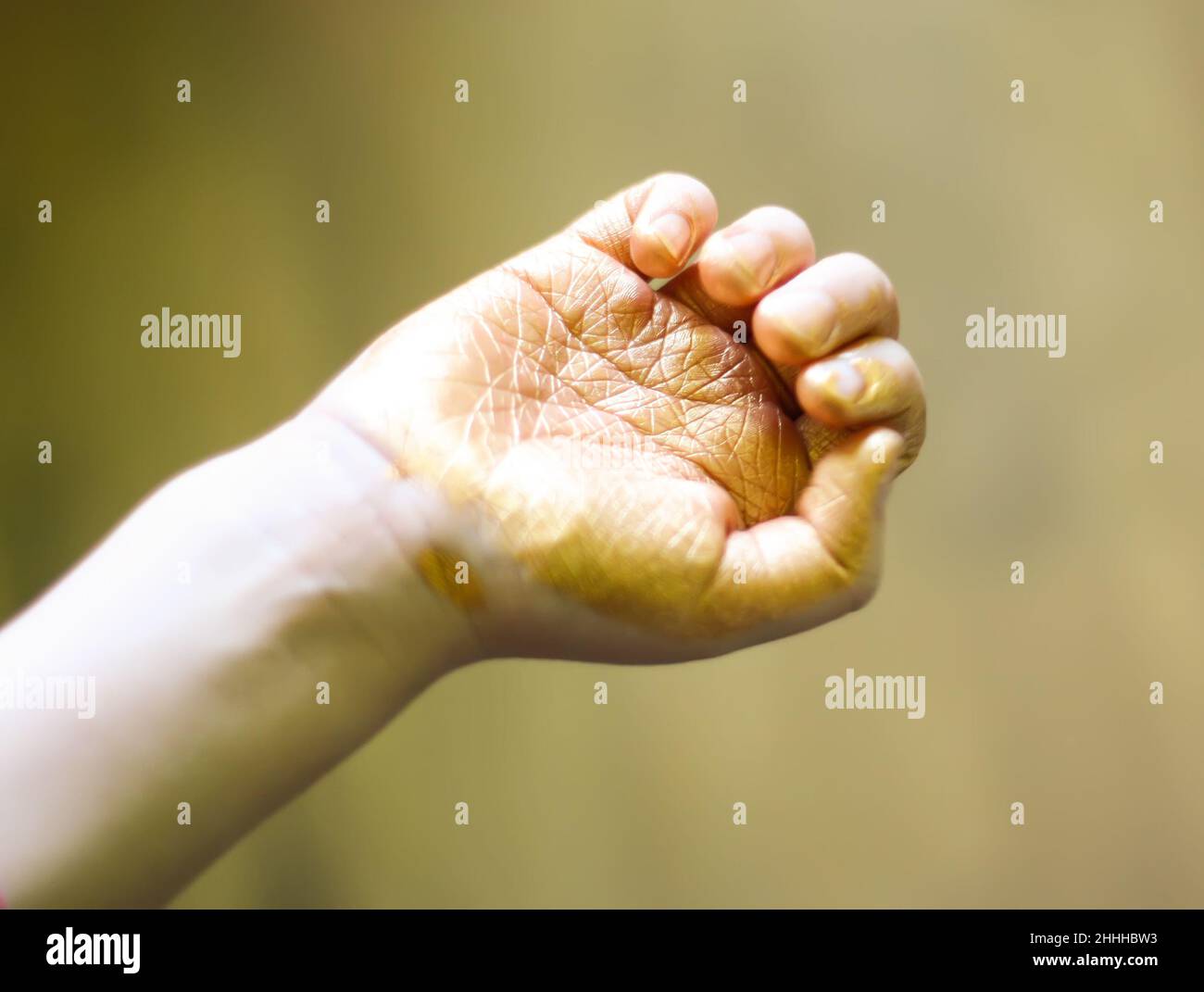 Child's hand in spots of golden paint in painting process. Stock Photo