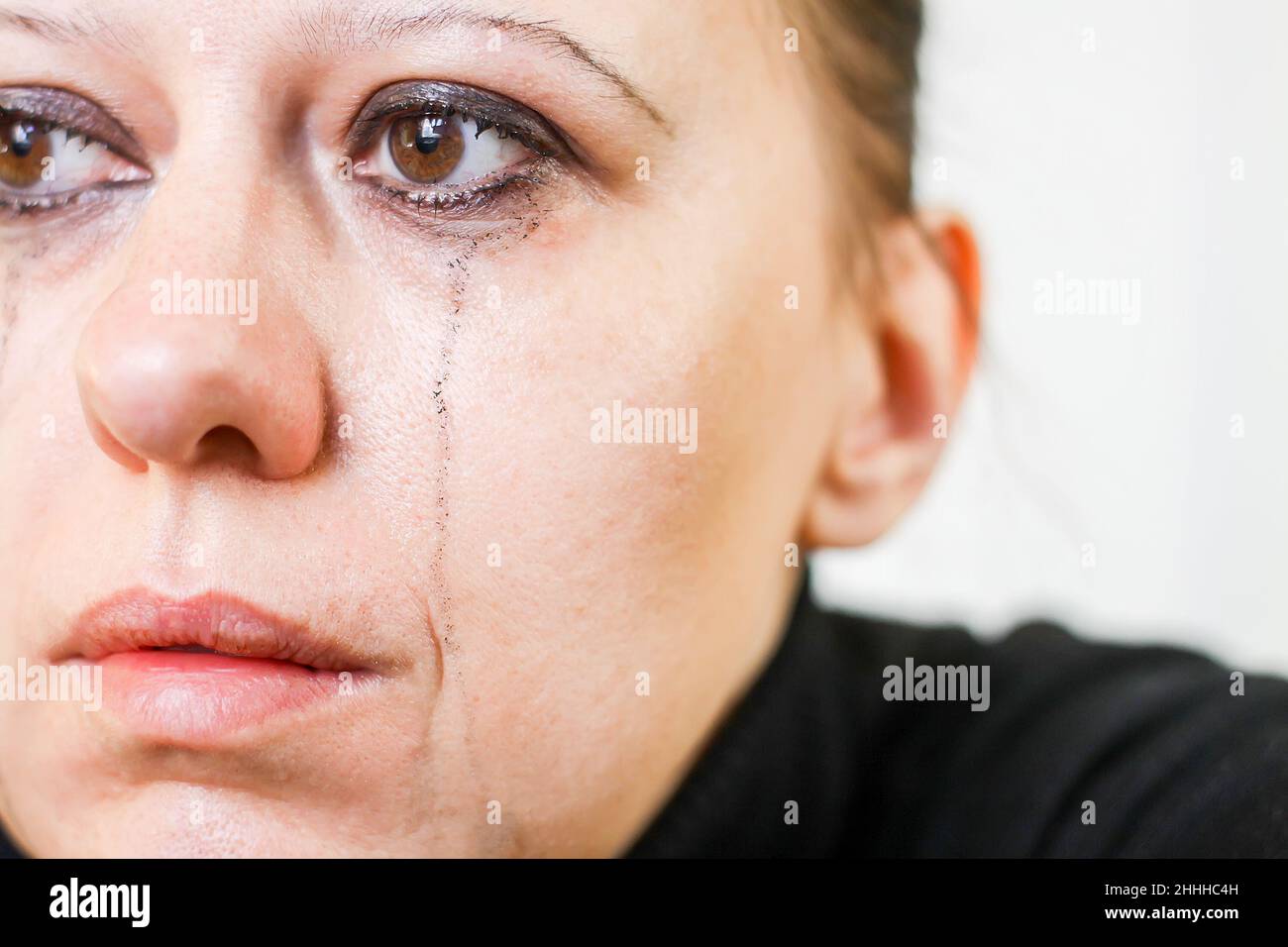 Closeup of crying woman with smudged makeup and black mascara