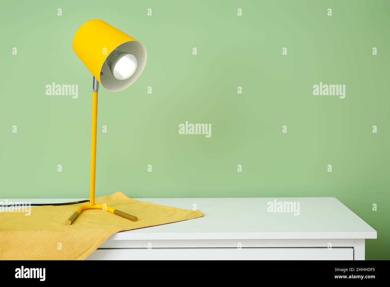 Glowing lamp on chest of drawers near color wall Stock Photo
