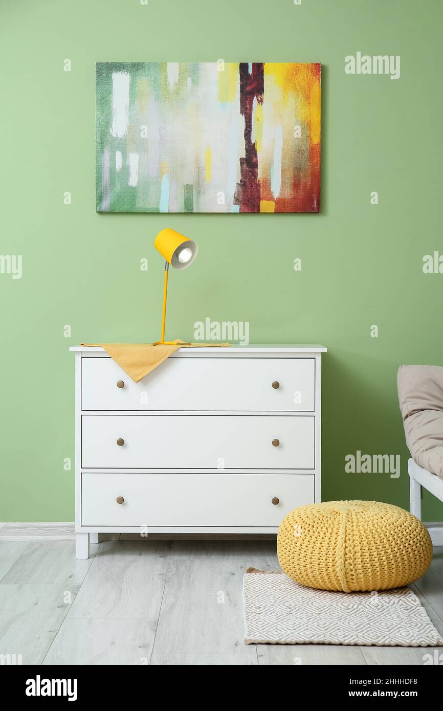 Modern glowing lamp on chest of drawers near color wall Stock Photo