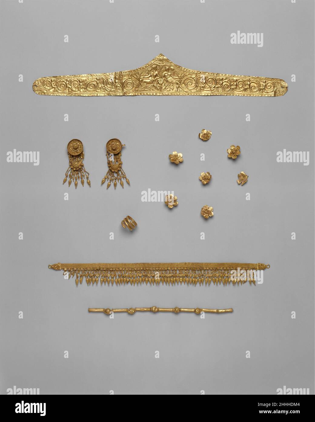 Set of jewelry ca. 330–300 B.C. Greek Pediment-shaped gold diadem (06.1217.1)Pair of gold earrings with disk and boat-shaped pendant (06.1217.11–.12)Gold strap necklace with seedlike pendants (06.1217.13)Gold necklace of beads and tubes (06.1217.3)Gold snake ring (06.1217.2)Seven gold rosettes (06.1217.4–.10)This group of jewelry is said to be from Madytos on the European side of the Hellespont. The gold diadem is richly worked in repoussé with an elaborate floral pattern. Dionysos, the god of wine, and his wife Ariadne sit in the center; muses playing musical instruments perch among vines alo Stock Photo