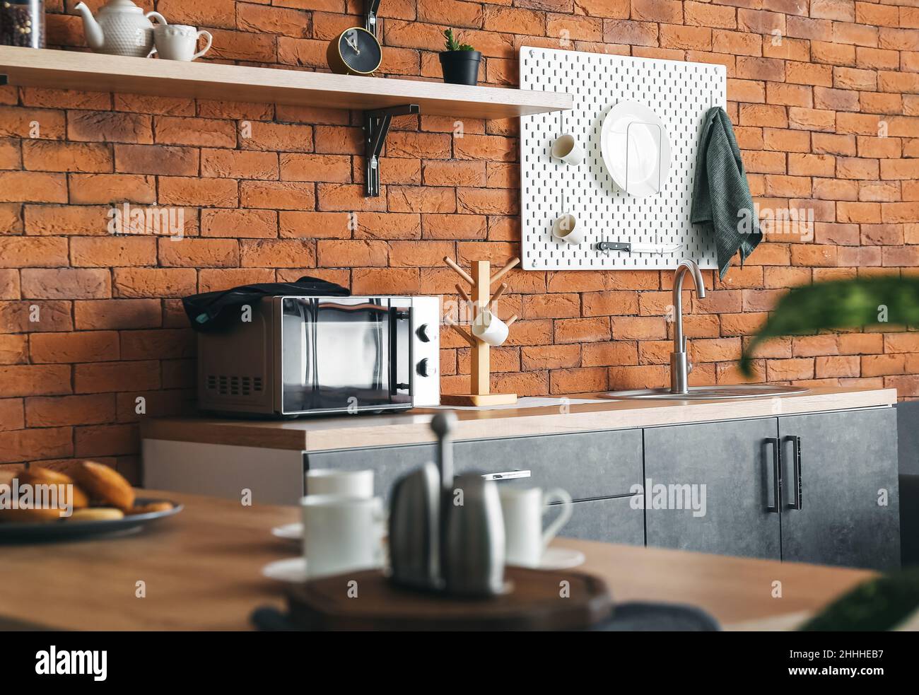 Interior of modern kitchen with counters and hanging pegboard on brick ...