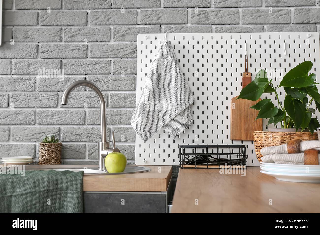 Modern counter and pegboard with kitchen utensils near grey brick wall ...