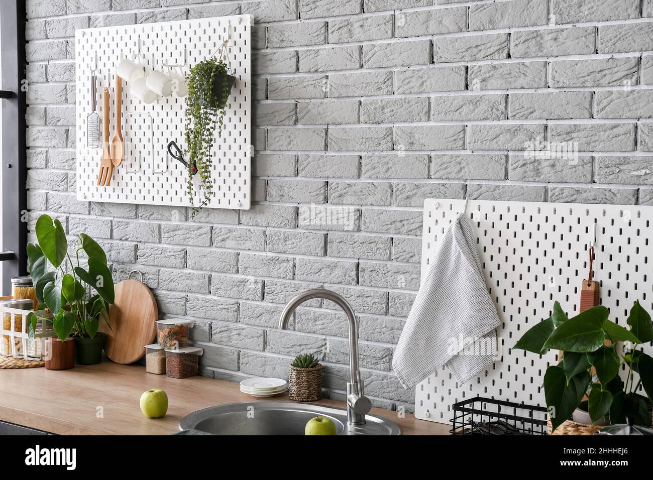 Modern counter and pegboards with kitchen utensils on grey brick wall ...