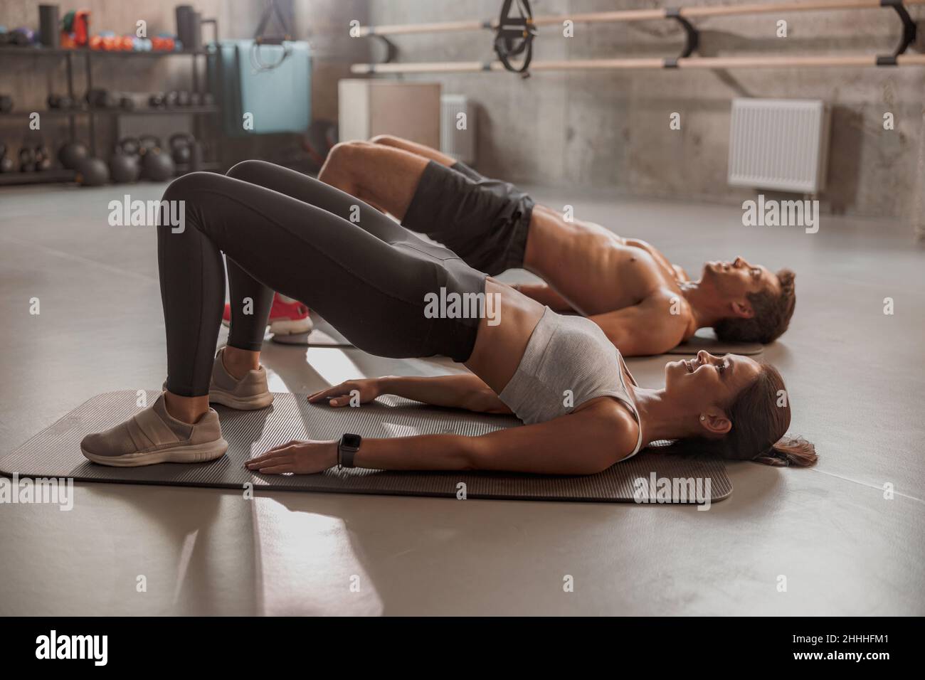 Young woman and sportive man doing abs exercises in the gym Stock Photo