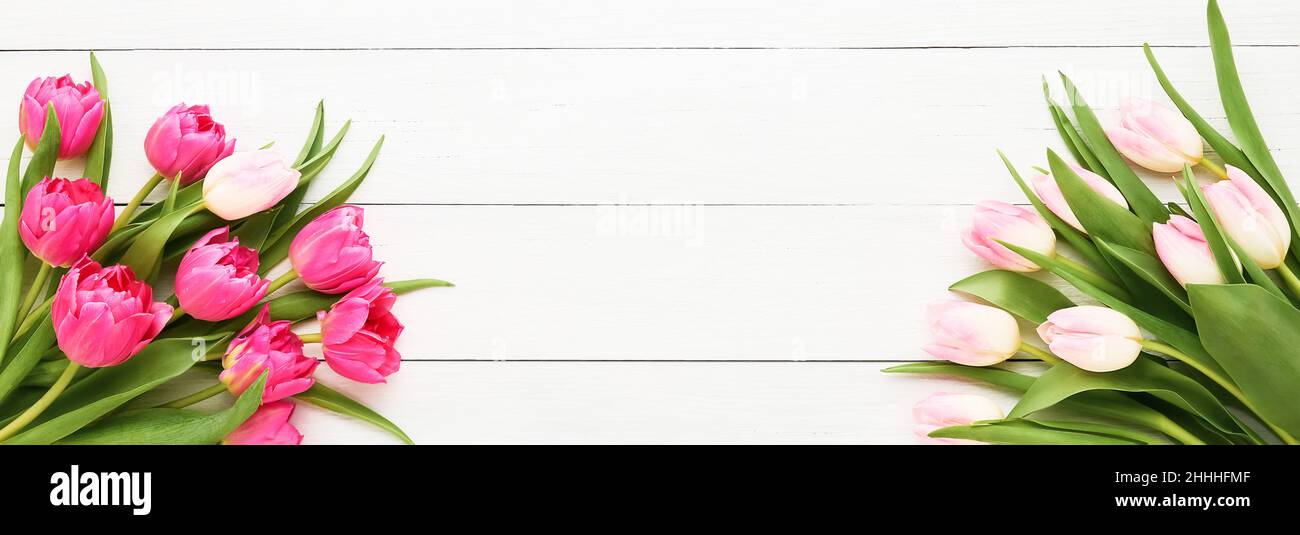Holiday banner. Bouquets of pink tulips on a white wooden background. Mothers day, Valentines Day, Birthday celebration concept. Copy space, top view Stock Photo