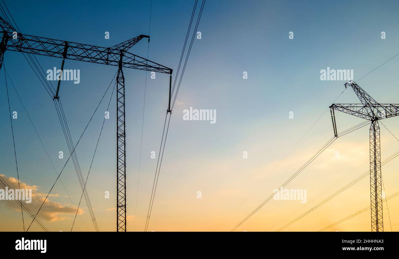 Dark silhouette of high voltage towers with electric power lines at ...