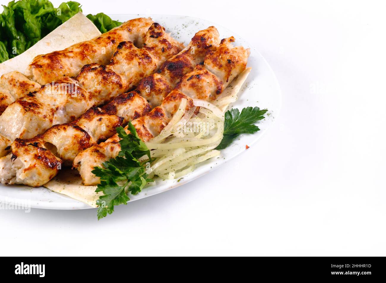 Homemade kebab on skewers with pita bread, onions, cabbage, vegetables, on a white plate on an