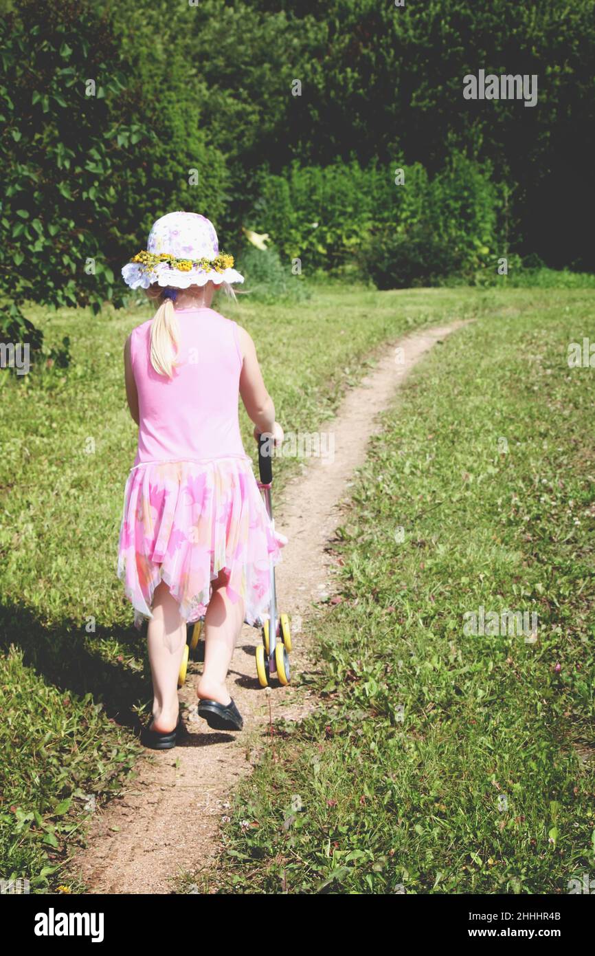 Cute little girl playing with her baby carriage outdoors. Stock Photo