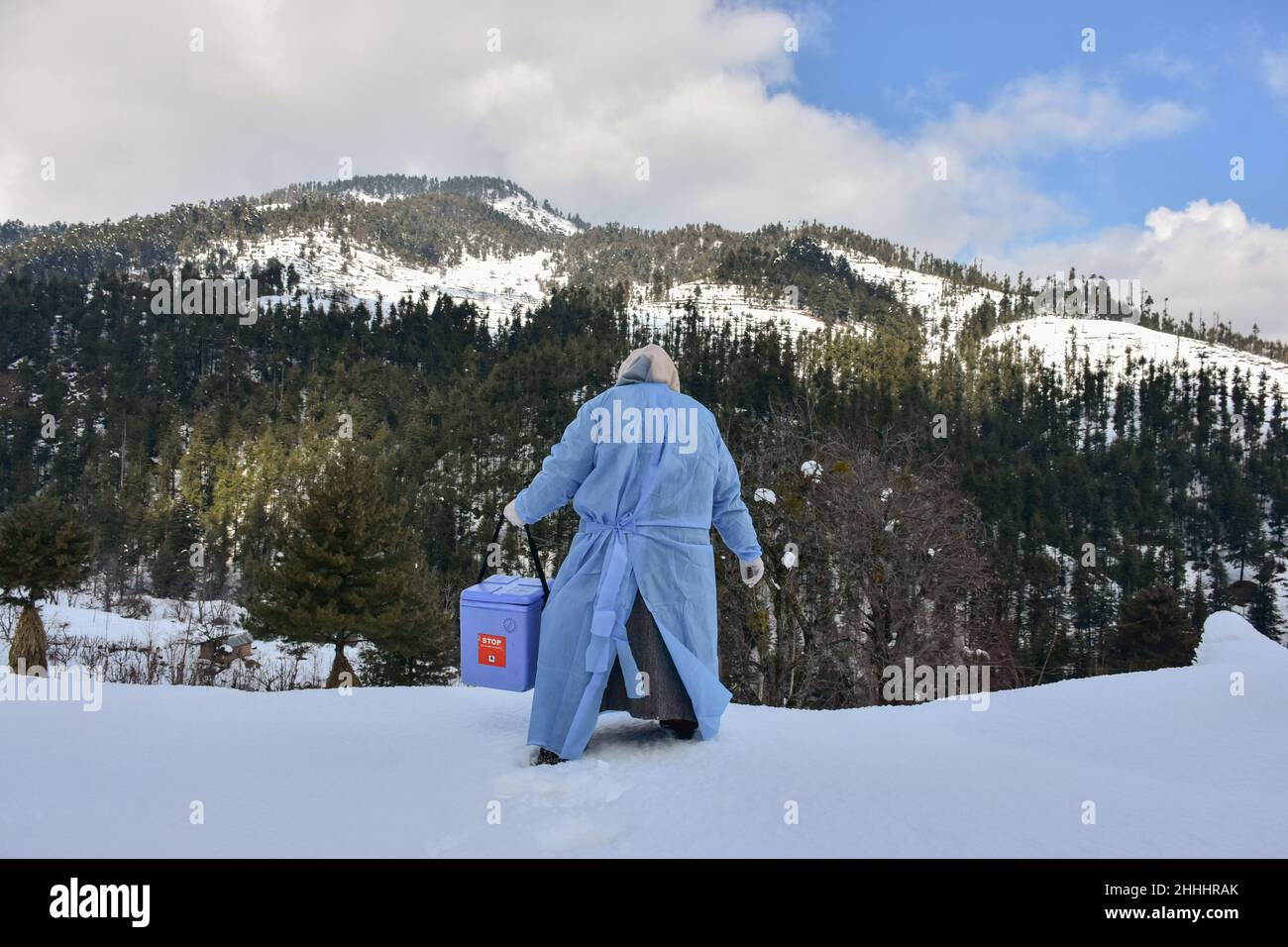 Kashmir, India - 24 Jan 2022, A health worker carries a Covishield Coronavirus vaccine box as she walks through a snow covered road during a door to door vaccination drive at a remote village in Budgam district, about 60kms from Srinagar. Despite excruciating cold and completely snow covered roads, the health workers in Kashmir valley are braving the harsh weather conditions and going door-to-door to vaccinate people against Coronavirus. The health department has decided campaign for the people above 60 who can't come to the vaccination centre because of illness or weather conditions. (Photo b Stock Photo