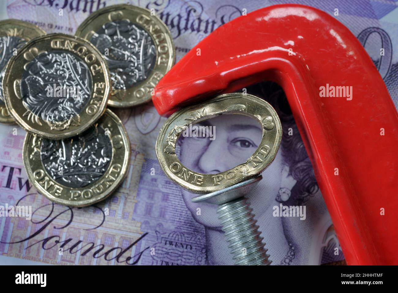 CRUSHED ONE POUND COIN IN JAWS OF A CLAMP RE THE ECONOMY COST OF LIVING WAGES INCOMES ETC UK Stock Photo
