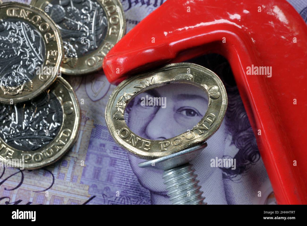 CRUSHED ONE POUND COIN IN JAWS OF A CLAMP RE THE ECONOMY COST OF LIVING WAGES INCOMES ETC UK Stock Photo