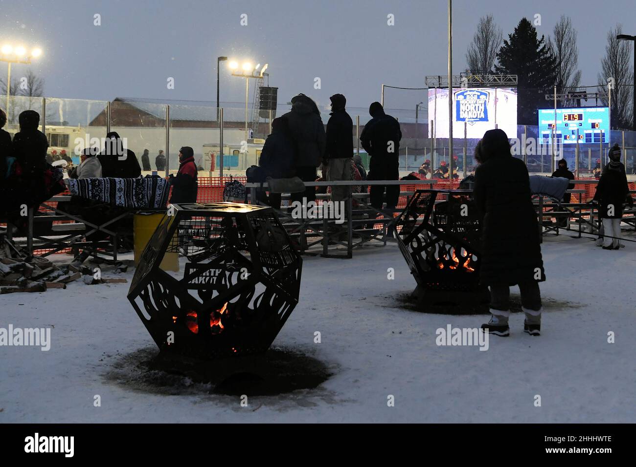 Fans warm up from subzero temperatures around fire pits during the 3rd annual Hockey Day North Dakota outdoor hockey event in Jamestown, ND. Youth, high school and college hockey teams from around North Dakota competed over two days. By Russell Hons/CSM Stock Photo