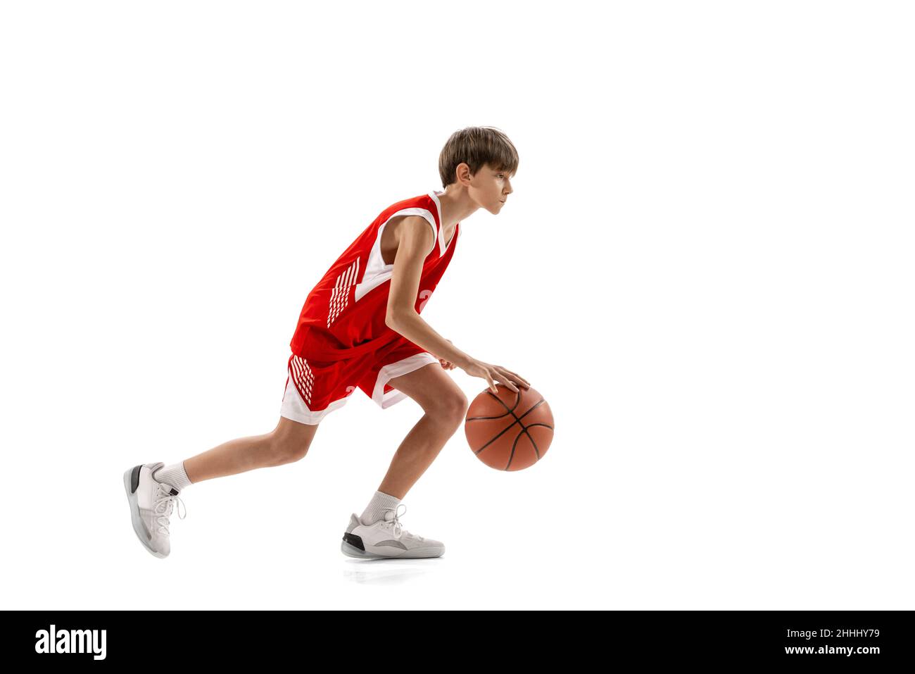 Full-length portrait of professional basketball player dribbling ball in motion, training isolated over white background Stock Photo