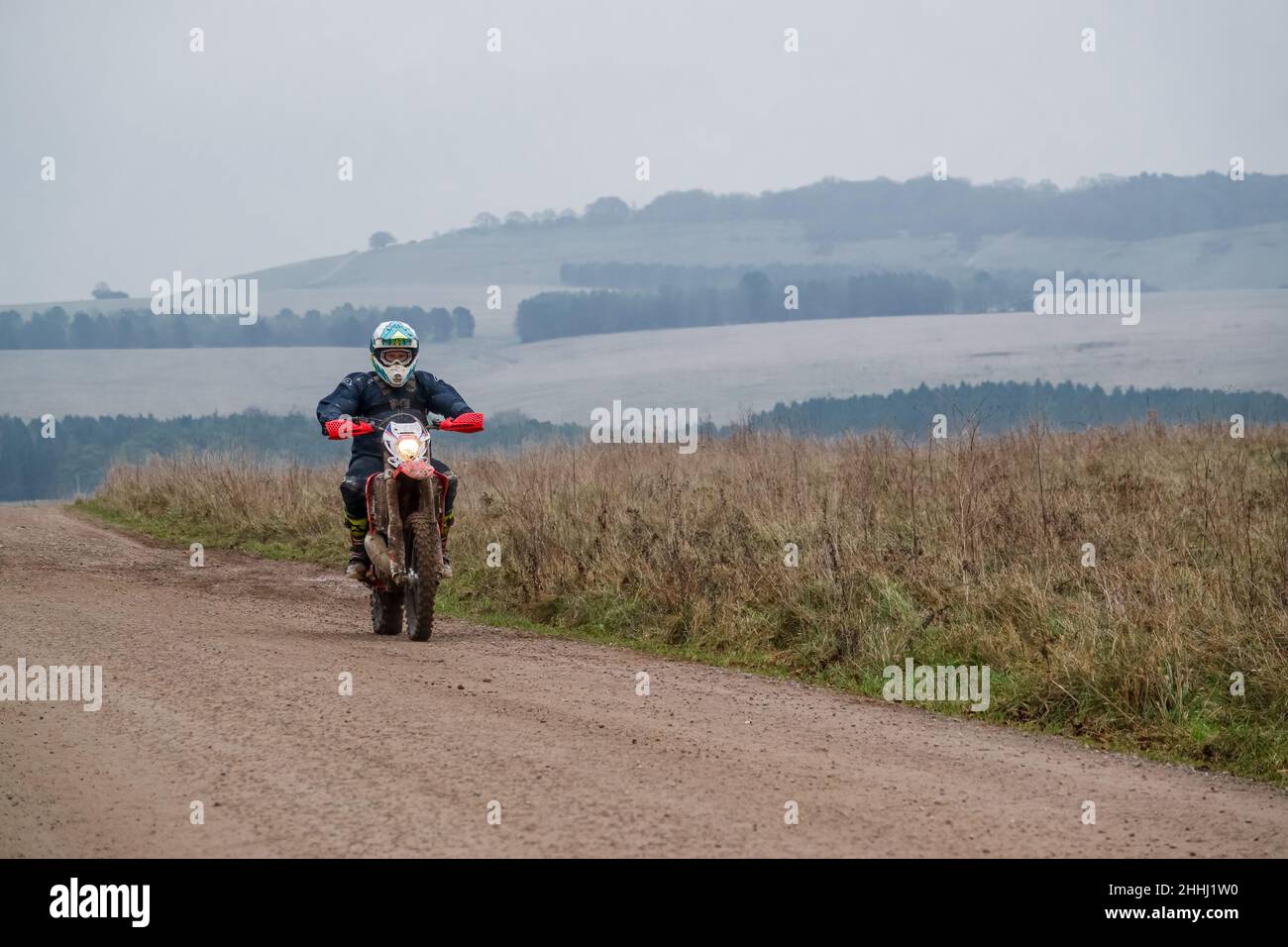 a motor cyclist (biker) riding their offroad motorbike along a stone