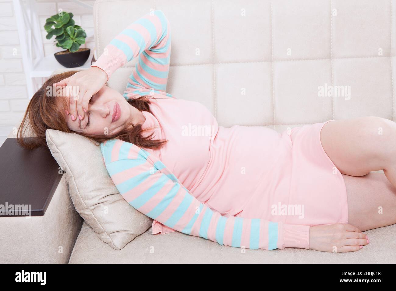 Middle aged woman having headache. Homey concept. Menopause and depression. Copy space Stock Photo