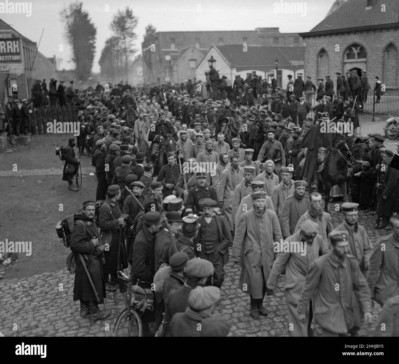 Captured German prisoners seen here being escorted by French and Belgium troops through a unnamed town in Northern France, A number of them have lost their caps and two or three are using scarves to cover their closely cropped heads. Circa October 20th 1914. Stock Photo