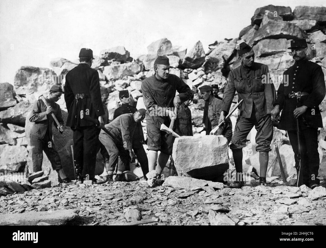 Convict film which was censored. A pictured drama by the Anchor Film Company, dealing with the escape of a convict from Portland, portions of which have been banned by the censor. The play was prepared in a private quarry, and the banned portions, which include the bribed warder scene, are vital. Pictured, the bribed warder passing instructions. Warder who has been bribed by outside friend, passing on plug of tobacco which contains instructions on how to escape. 21st December 1913. Stock Photo