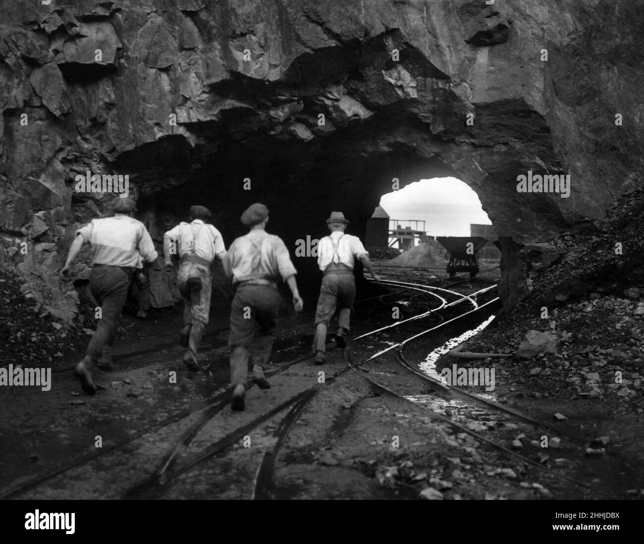 Men running through a tunnel, cut out by the quarrymen, to take cover during the blasting. Penlee stone quarry, Newlyn. 26th February 1923. Stock Photo