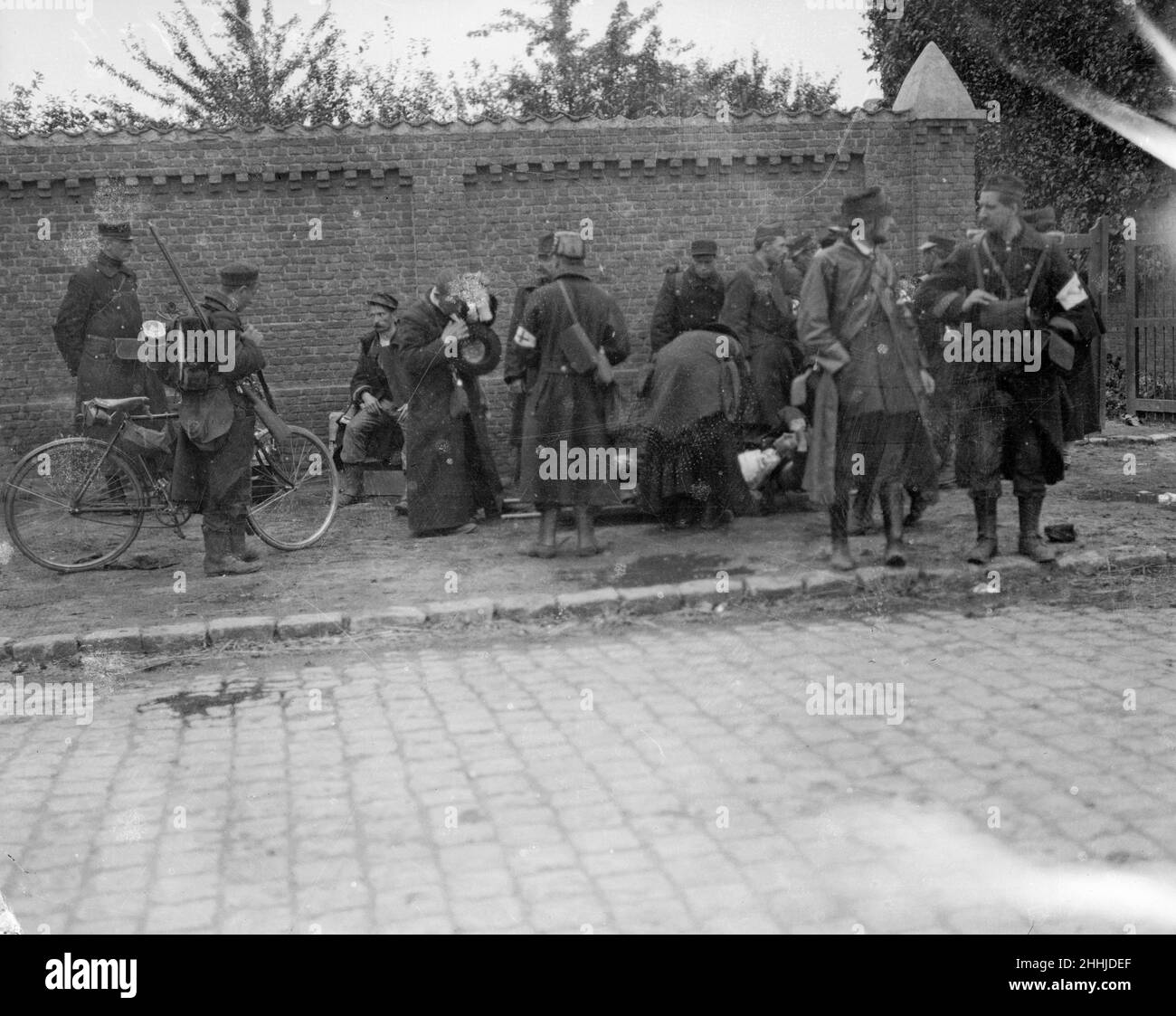 Battle of Hofstade. Priests attended to an injured soldier as a cycle patrol set out. Close by stands the King of the Belgians watching the preparations. Stock Photo