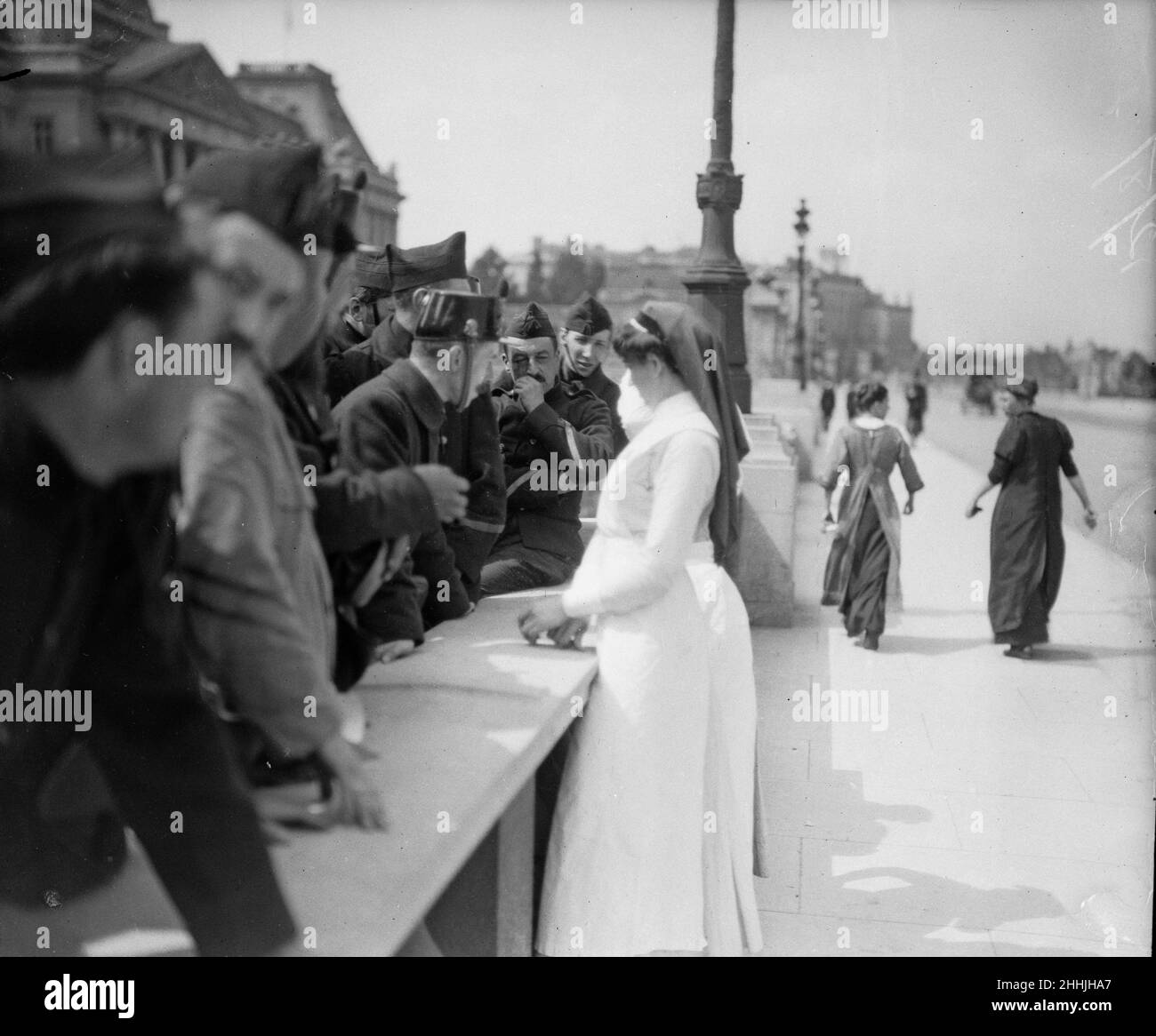 A batch of English nurses seen here talking to Belgian soldiers outside the Royal Palace before leaving Brussels for the front to tend to the wounded. The inhabitants gave them a splendid welcome, and everyone commented on how kind and sympathetic they looked. Their soldiers, they felt would be in skilful hands. Every man who returns to the capitasl from Liege is regarded as a hero and is made to tell again and again the wonderful story of how the Germans were repulsed by a heroic little band of defenders. August 1914 Stock Photo