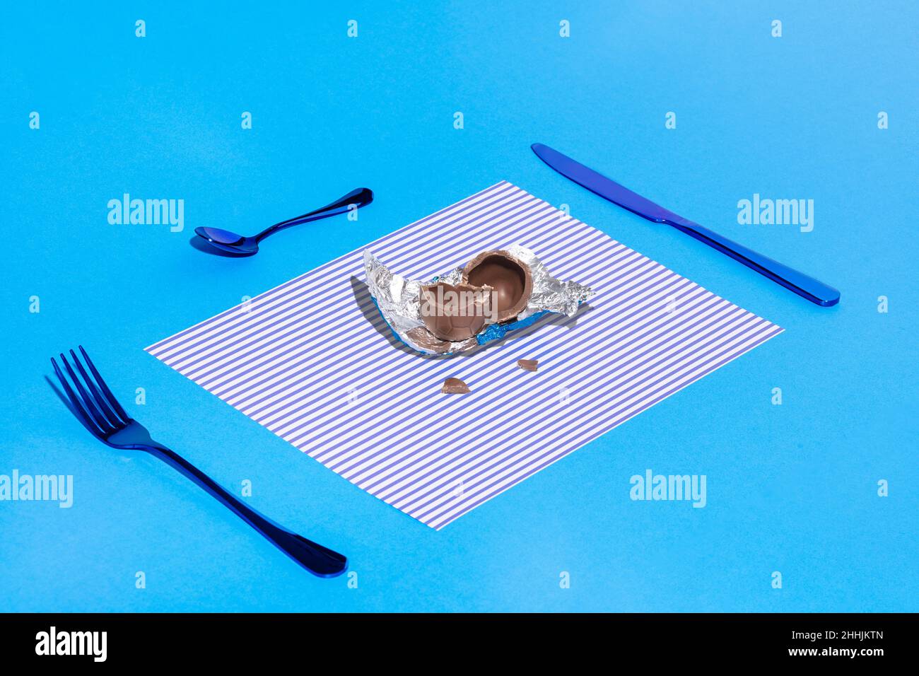 Broken chocolate egg on a plate on a blue background Stock Photo