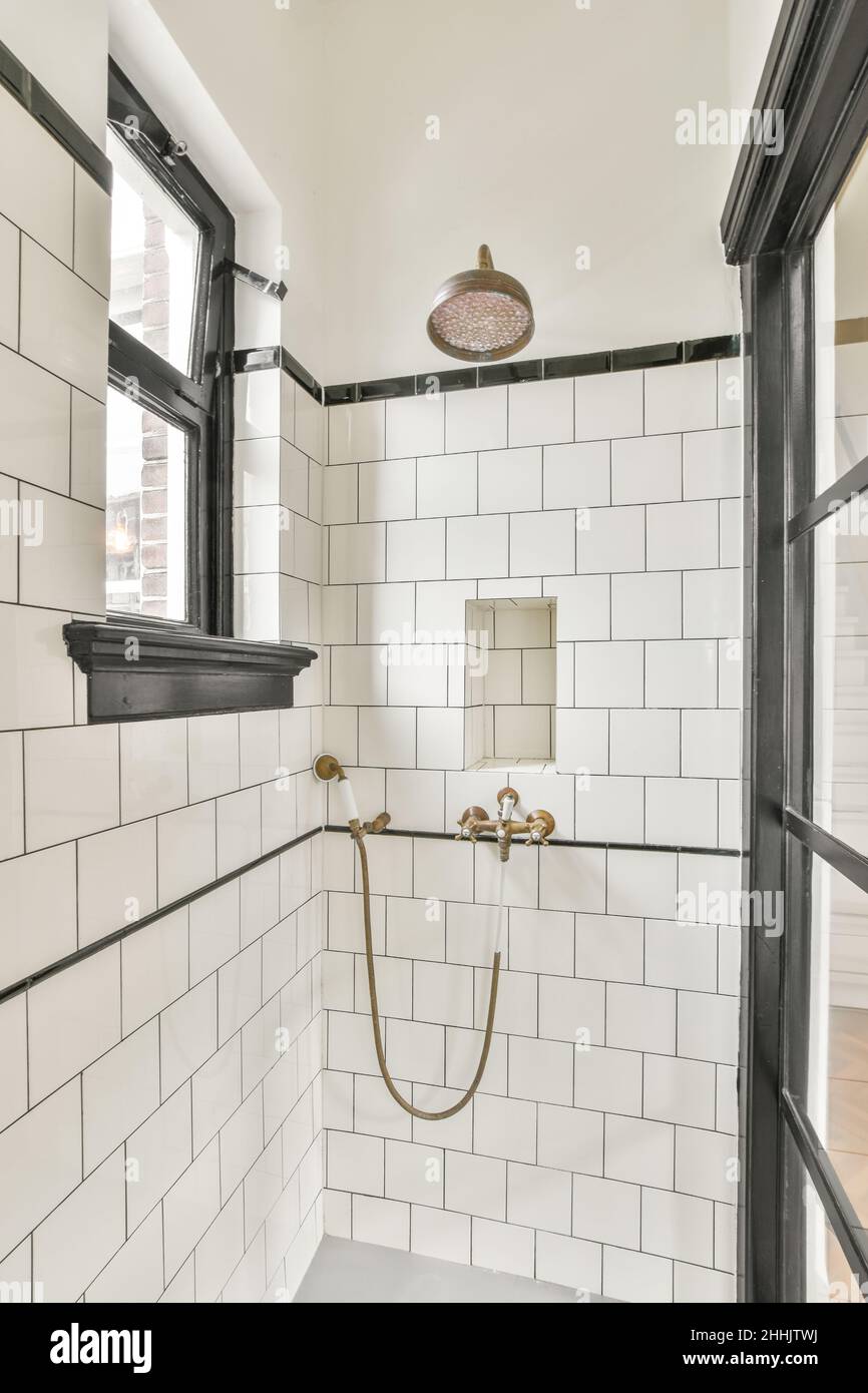 https://c8.alamy.com/comp/2HHJTWJ/interior-of-stylish-white-tiled-bathroom-with-rain-shower-head-and-handheld-spray-faucets-set-mounted-on-wall-2HHJTWJ.jpg