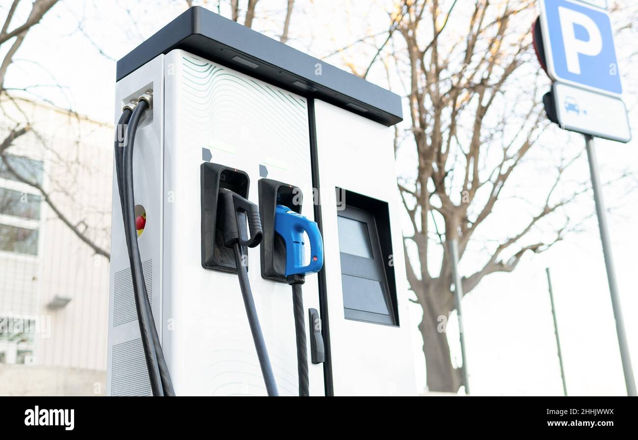 White charging point with two connections in city parking lot with no